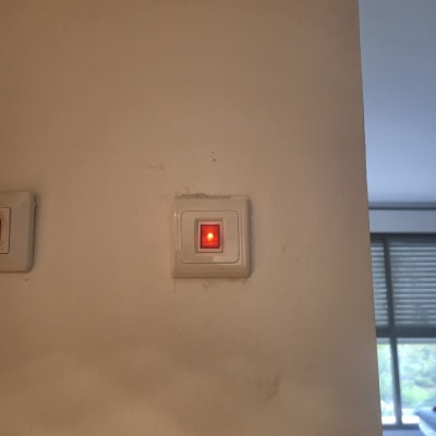 מתג חשמלי עם נורית חיווי אדומה על קיר