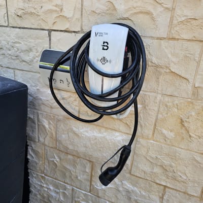 מטען לרכב חשמלי מותקן על קיר עם כבל שחור