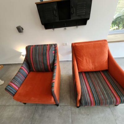 שני כורסאות כתומות עם פסים צבעוניים על רצפת אריחים אפורה