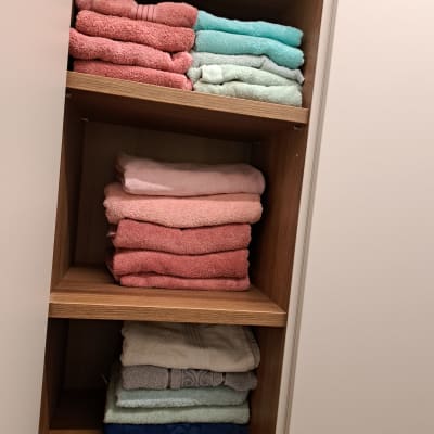 מגבות צבעוניות מסודרות בארון עץ פתוח