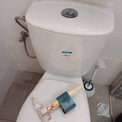 חלקי צנרת על מכסה אסלה בחדר אמבטיה