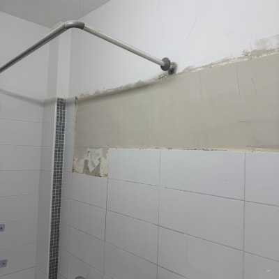 קיר אמבטיה עם אריחים וצינור מקלחת מותקן