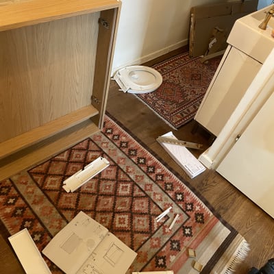 חלקי רהיטים להרכבה עם הוראות וכלים על שטיח