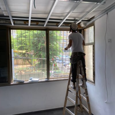 עובד על סולם מתקין תקרת גבס