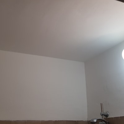 קיר צבוע בלבן עם מנורה עגולה מוארת