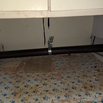 צינור שחור מתחת לכיור עם תושבת מתכת