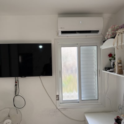 מזגן מותקן על קיר מעל חלון בחדר