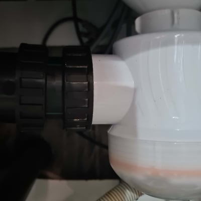 צינור פלסטיק לבן עם מחבר שחור מתחת לכיור