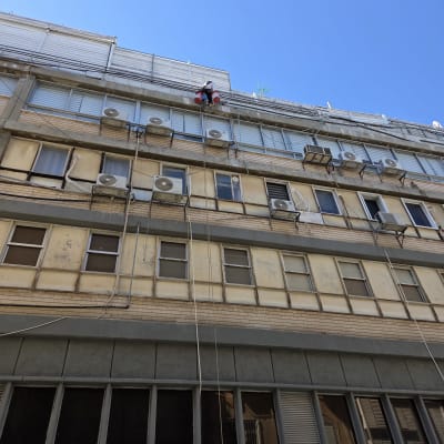 אדם עובד בגובה על בניין עם חבלי בטיחות