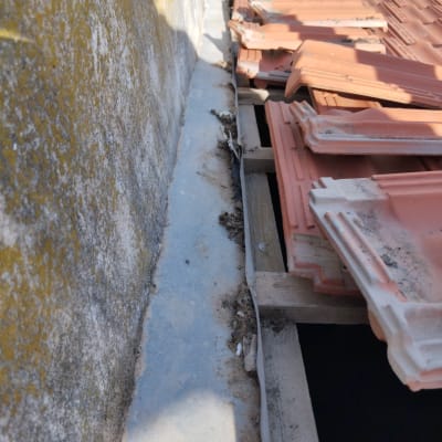 רעפים כתומים על גג עם קיר בטון