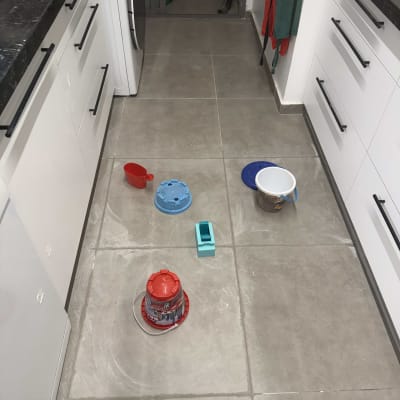 כלים על רצפת מטבח, דליים ומיכלים שונים.