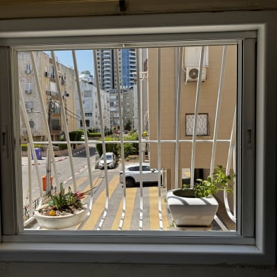 סורגי מתכת על חלון עם עציצים