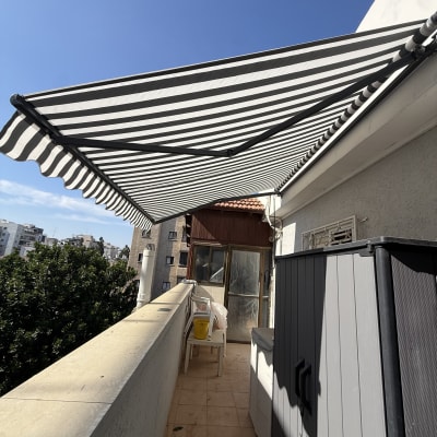 מרפסת עם סוכך פסים בשחור ולבן ביום שמשי