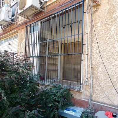 סורגים מותקנים על חלון בניין עם מזגנים