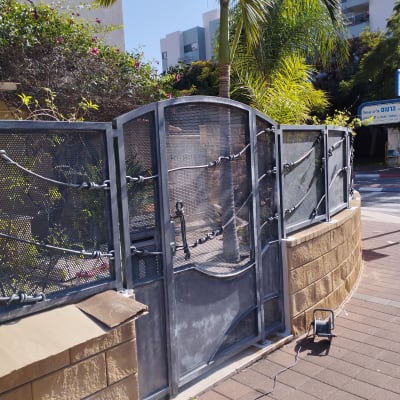 שער מתכת עם כבל חשמל ומנורה על הקרקע