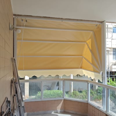 סוכך צהוב מותקן במרפסת עם מעקה זכוכית