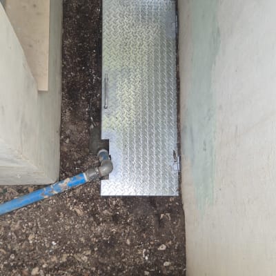 מכסה מתכת על הקרקע ליד צינור כחול