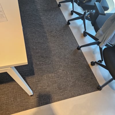 שטיח כהה על רצפה בהירה ליד כיסאות משרדיים
