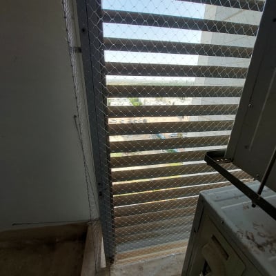 רשת מתכת מותקנת על חלון למניעת כניסת יונים