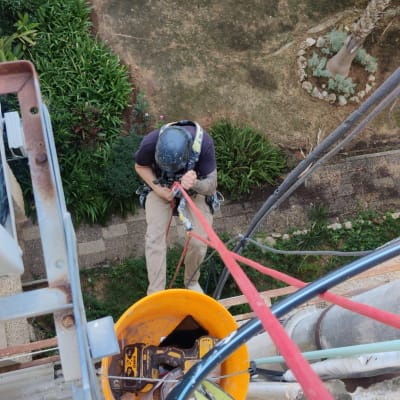 אדם עם קסדה מטפס על חבלים עם דלי כלים