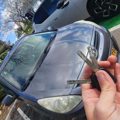 מפתח רכב מוחזק מול מכונית חונה