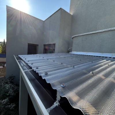 גג מתכת עם ברגים ליד קיר חיצוני של מבנה