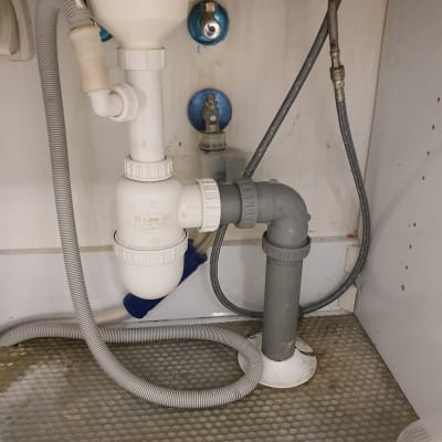 צנרת מתחת לכיור עם ברזים וצינורות פלסטיק