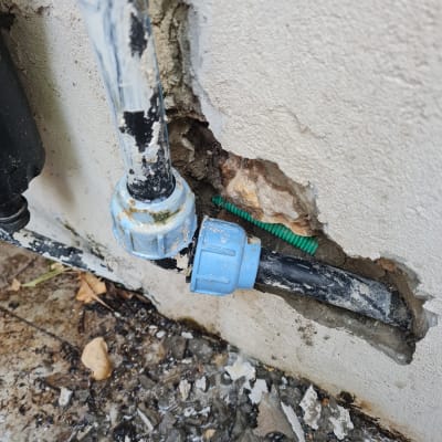 צינור מים עם חיבור פלסטיק כחול בקיר שבור