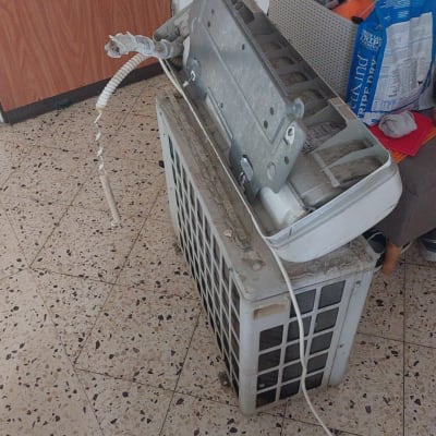 יחידת מזגן מפורקת על הרצפה עם כבלים חשופים