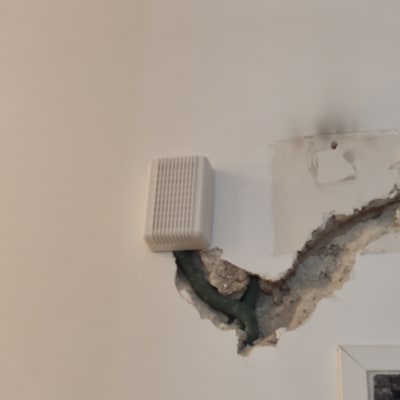 צינור ירוק בקיר עם חור ותיבה לבנה