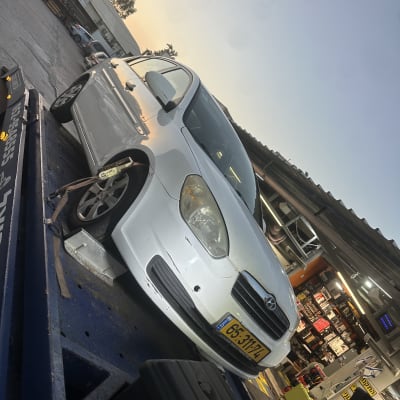 רכב לבן על מעלית במוסך עם ציוד תיקון סביבו