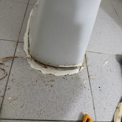 בסיס אסלה עם חומר איטום וכלי עבודה על הרצפה