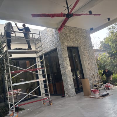 שני אנשים על פיגום צובעים תקרה בחוץ