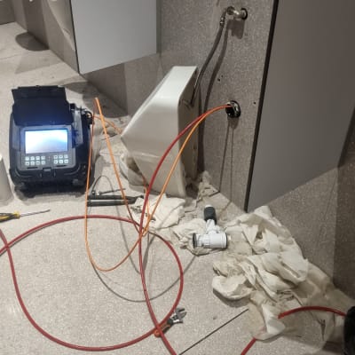 כלי עבודה וצינורות ליד אסלה בשירותים