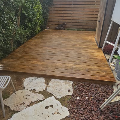 דק עץ בגינה עם שביל אבנים וחצץ אדום