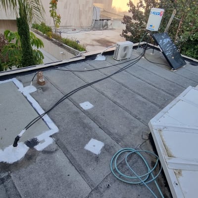 איטום גג עם חומר לבן סביב חיבורים וצינורות