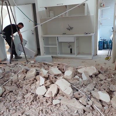 שיפוץ מטבח עם הריסות על הרצפה ואדם בעבודה