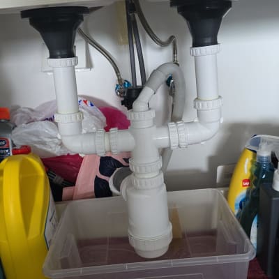 צנרת מתחת לכיור עם חיבורים וכלים לניקוי