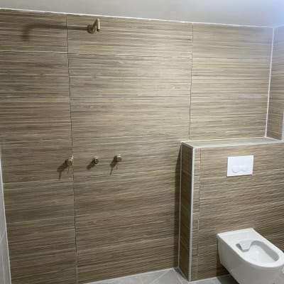 חדר אמבטיה עם אריחים חומים ואסלה תלויה