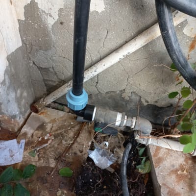 צינור מים עם מחבר פלסטיק כחול על קיר בטון