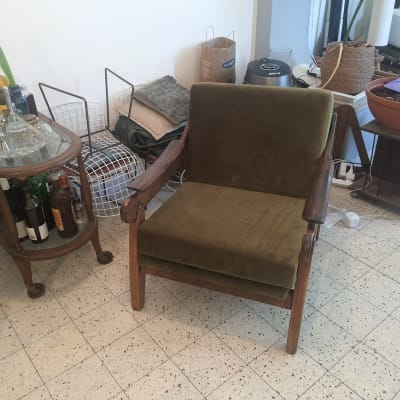 כיסא מרופד עם משענת וידיות עץ בחדר פנימי