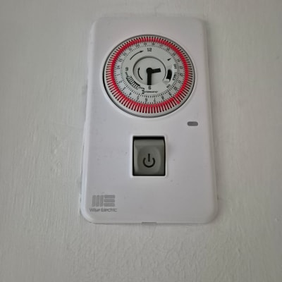 טיימר חשמלי עם כפתור הפעלה על קיר לבן