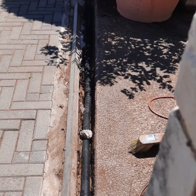 צינור שחור מונח בתעלה לצד מדרכה