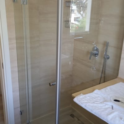 מקלחון זכוכית עם ברז ומגבת על השיש