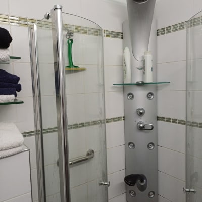 תא מקלחת עם ראש מקלחת ומדף