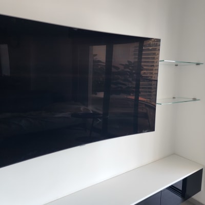 מדף זכוכית ליד טלוויזיה על קיר לבן