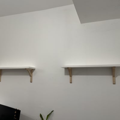 מדפים לבנים מותקנים על קיר עם תומכים מעץ