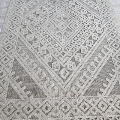 שטיח עם דוגמה גיאומטרית על רצפה אפורה