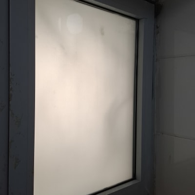 חלון זכוכית עם מסגרת מתכת בחדר מואר חלקית