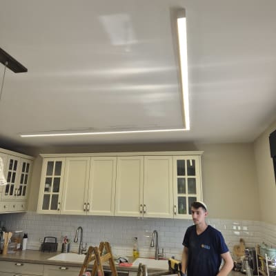 חשמלאי עומד ליד סולם במטבח עם תאורה מותקנת